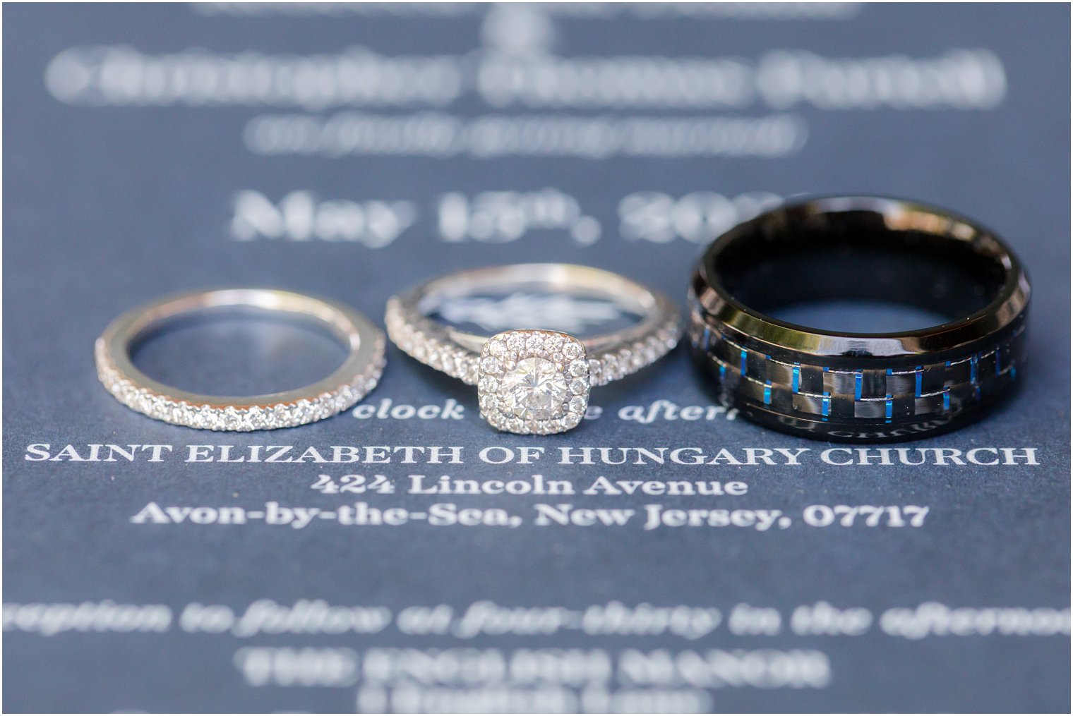 rings rest on navy blue wedding invitation 
