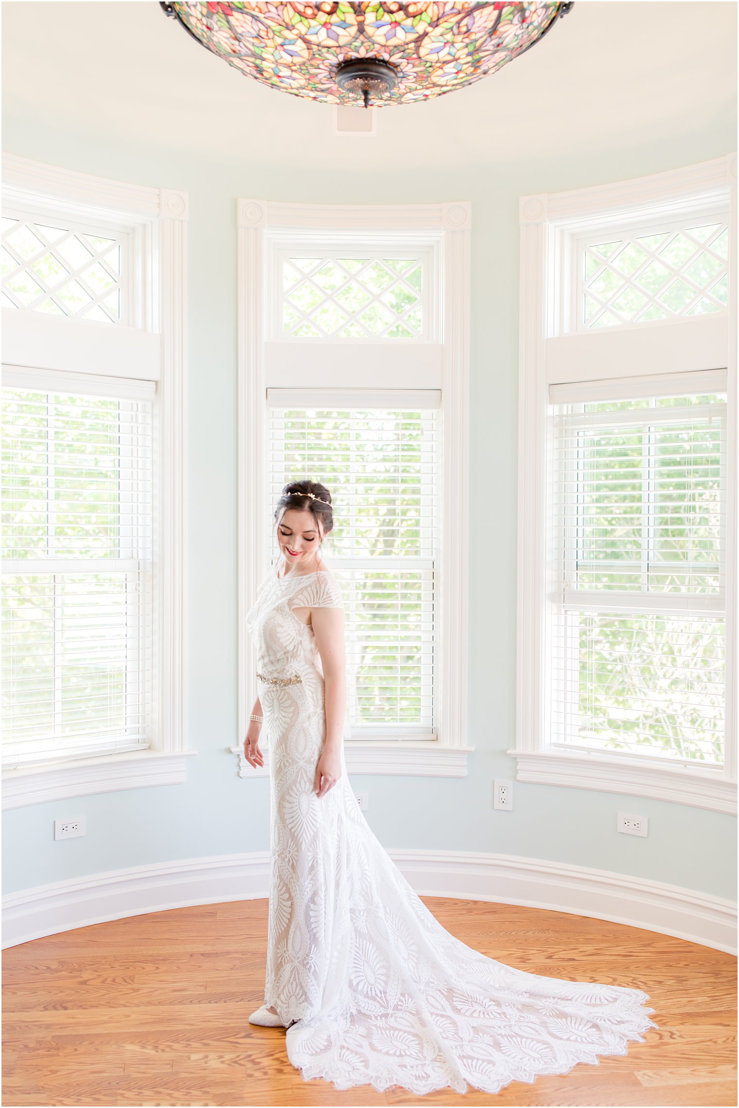 bride poses in bay window at home
