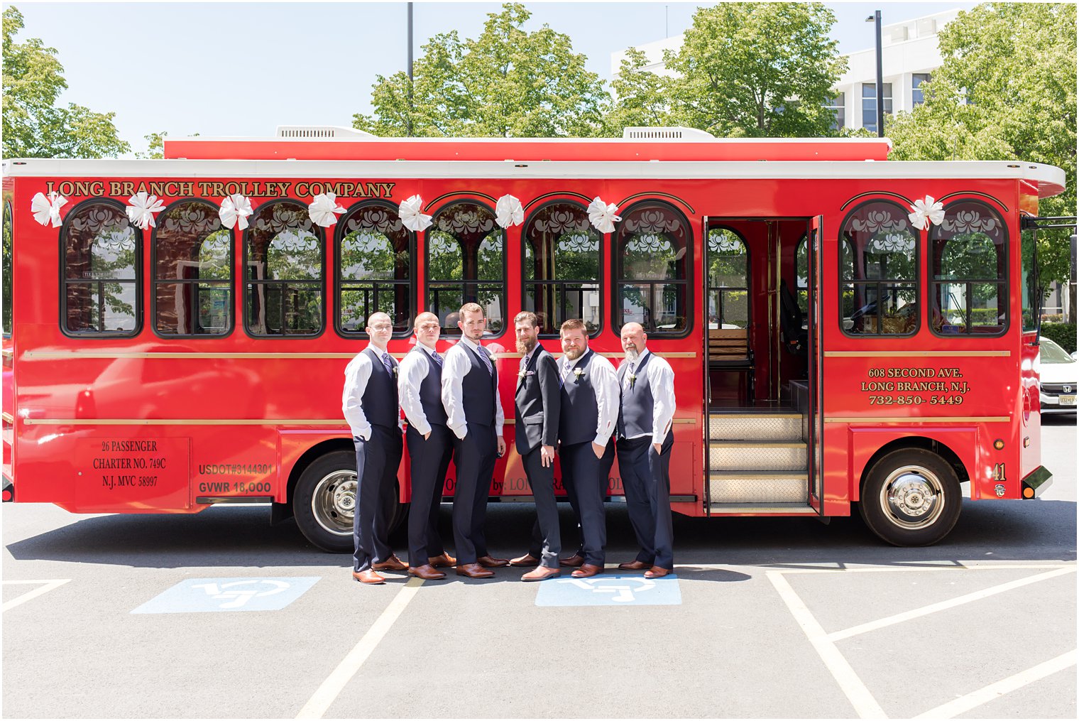 groom and groomsmen pose outside red trolley before Ocean Township NJ wedding