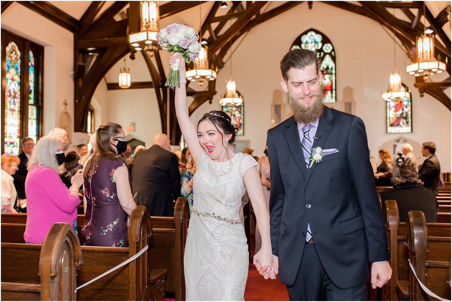 newlyweds cheer walking down aisle during traditional church wedding in New Jersey