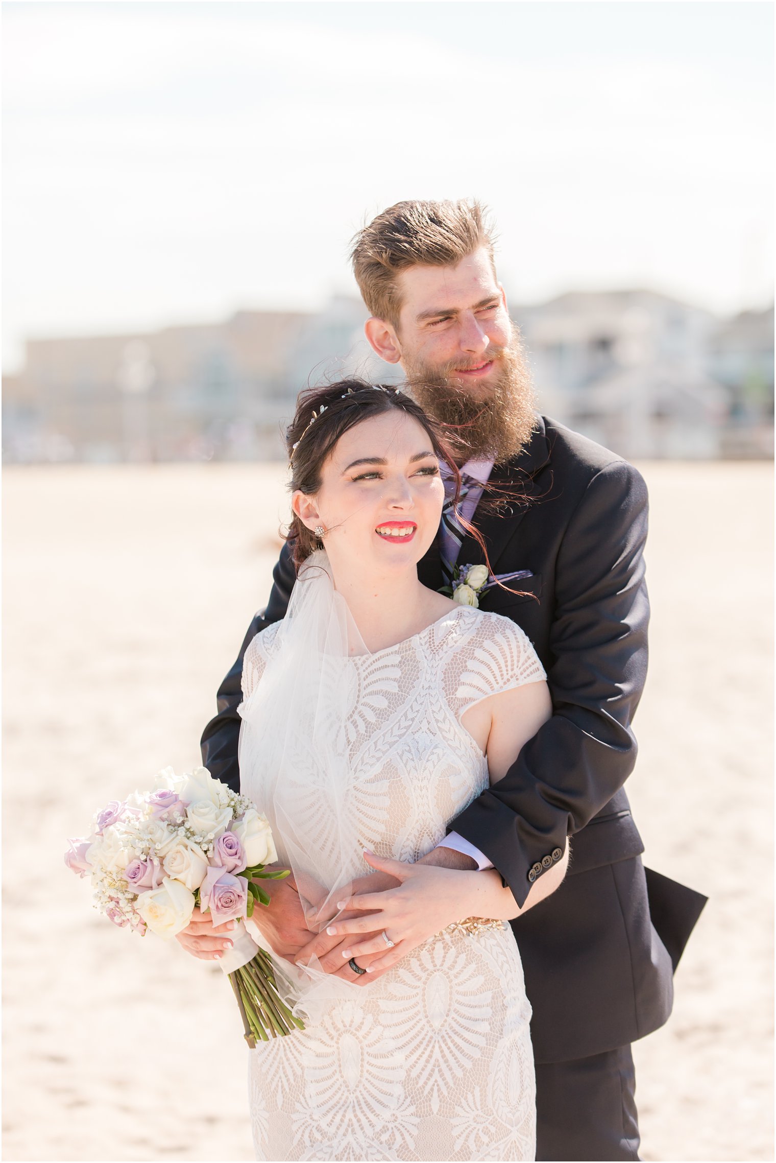 groom hugs bride on beach during NJ wedding photos