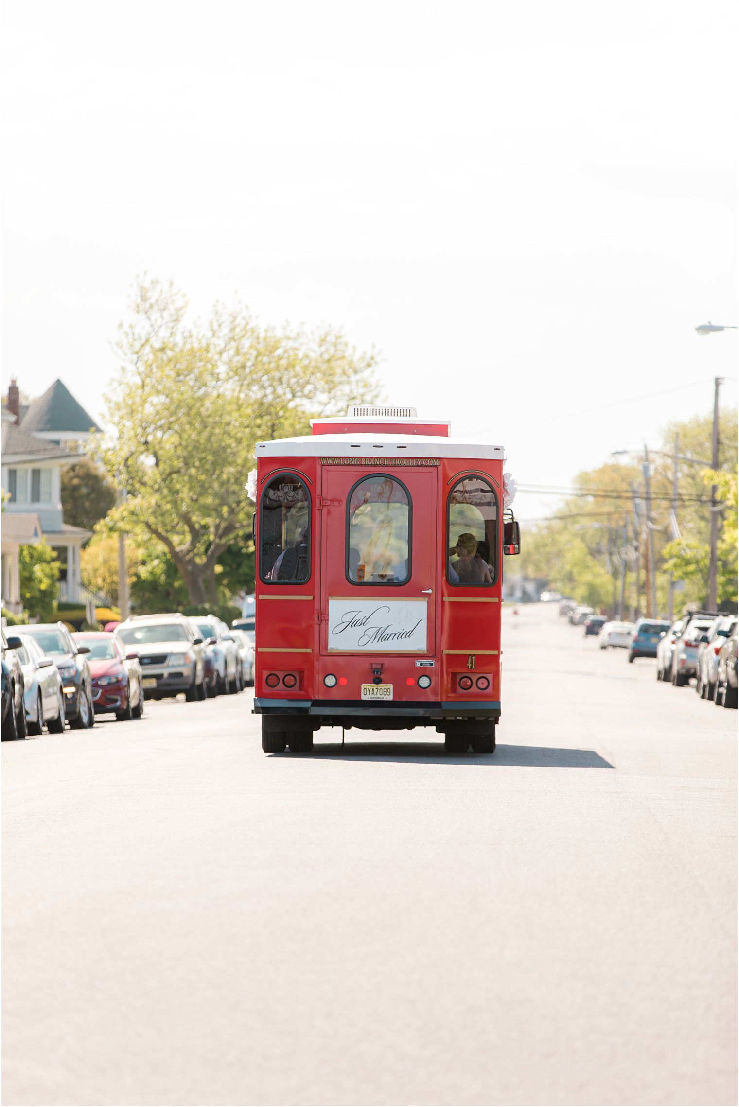 wedding party rides down road in New Jersey on red trolley