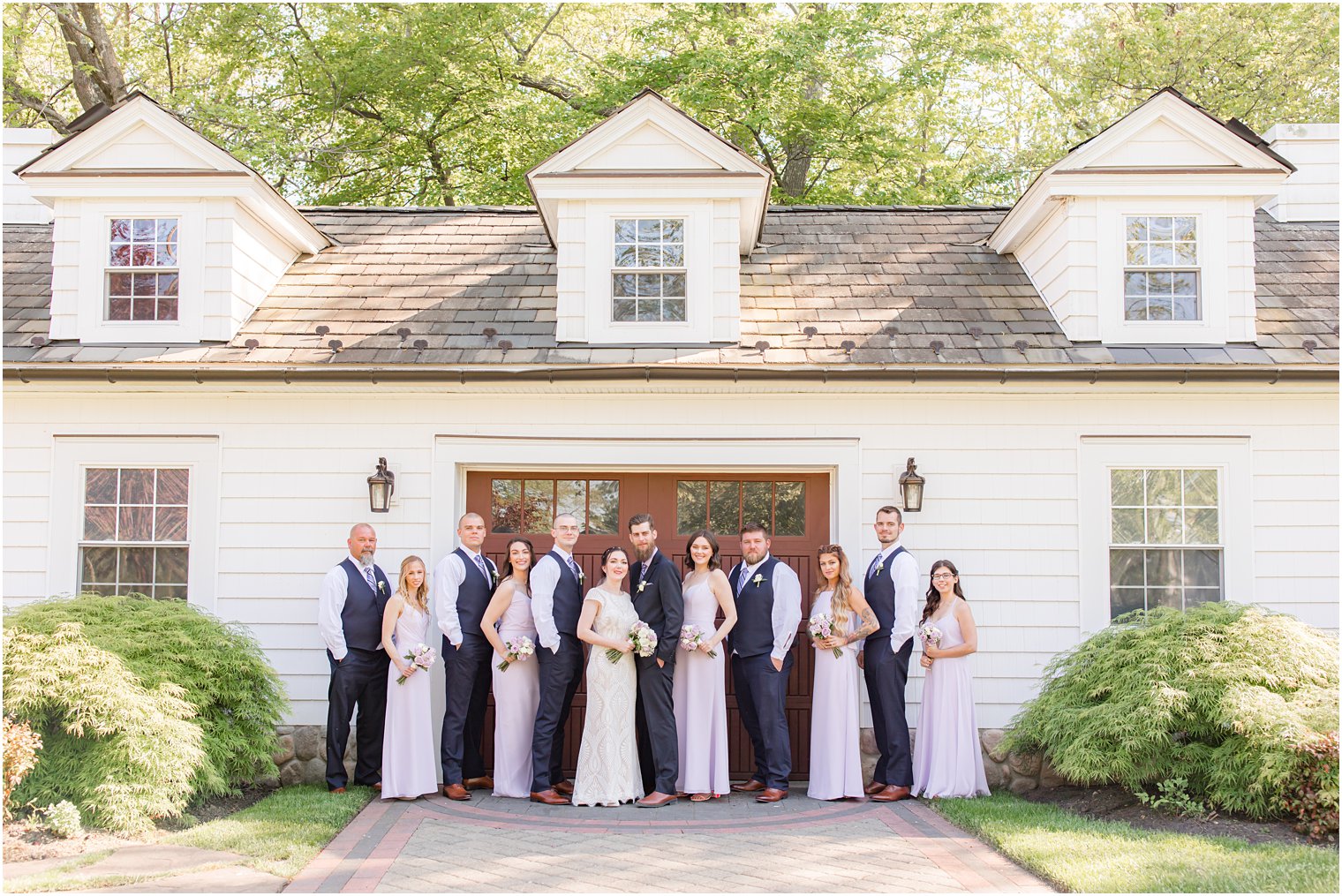 bridal party in purple dresses pose outside The English Manor