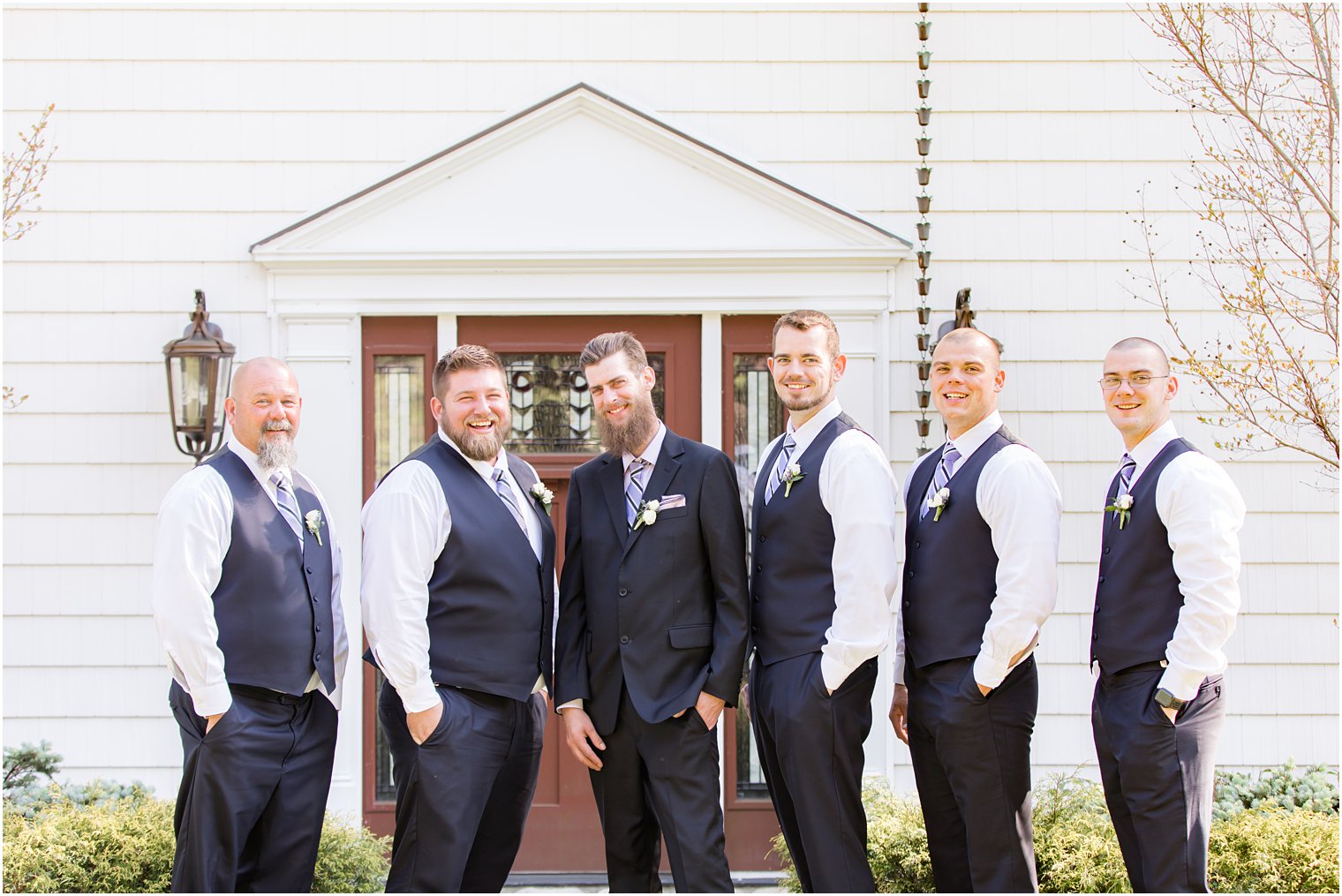 groom poses with groomsmen outside The English Manor