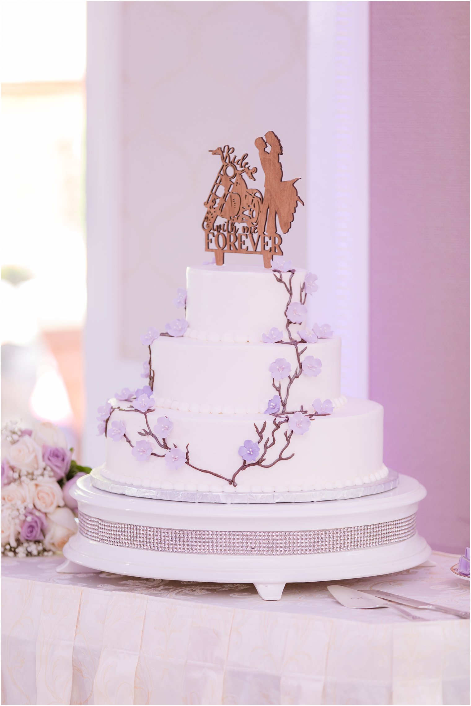 wedding cake with purple florals and wooden cake topper