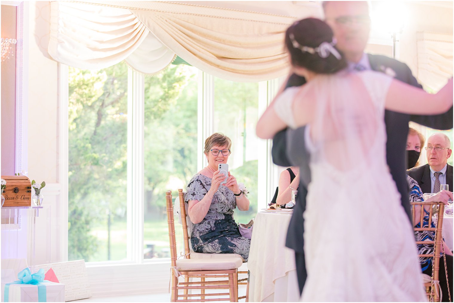 bride looks at mom taking photo during dance with dad