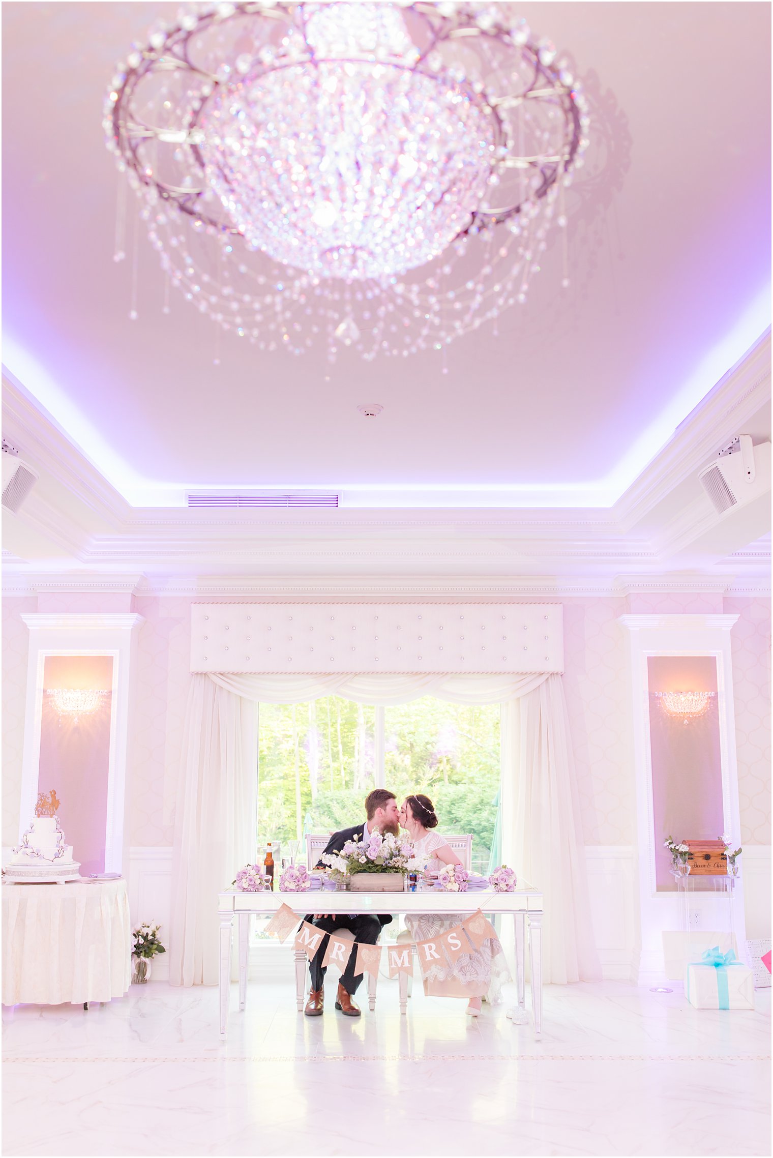 bride and groom kiss at swetheeart table in ballroom at The English Manor