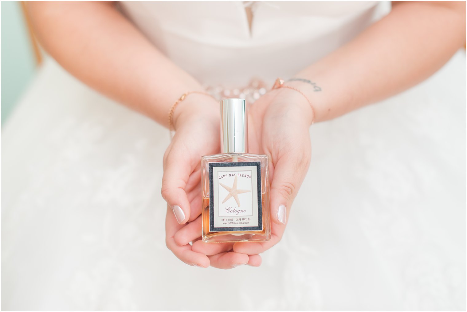 bride holds bottle of perfume with sea star on the front