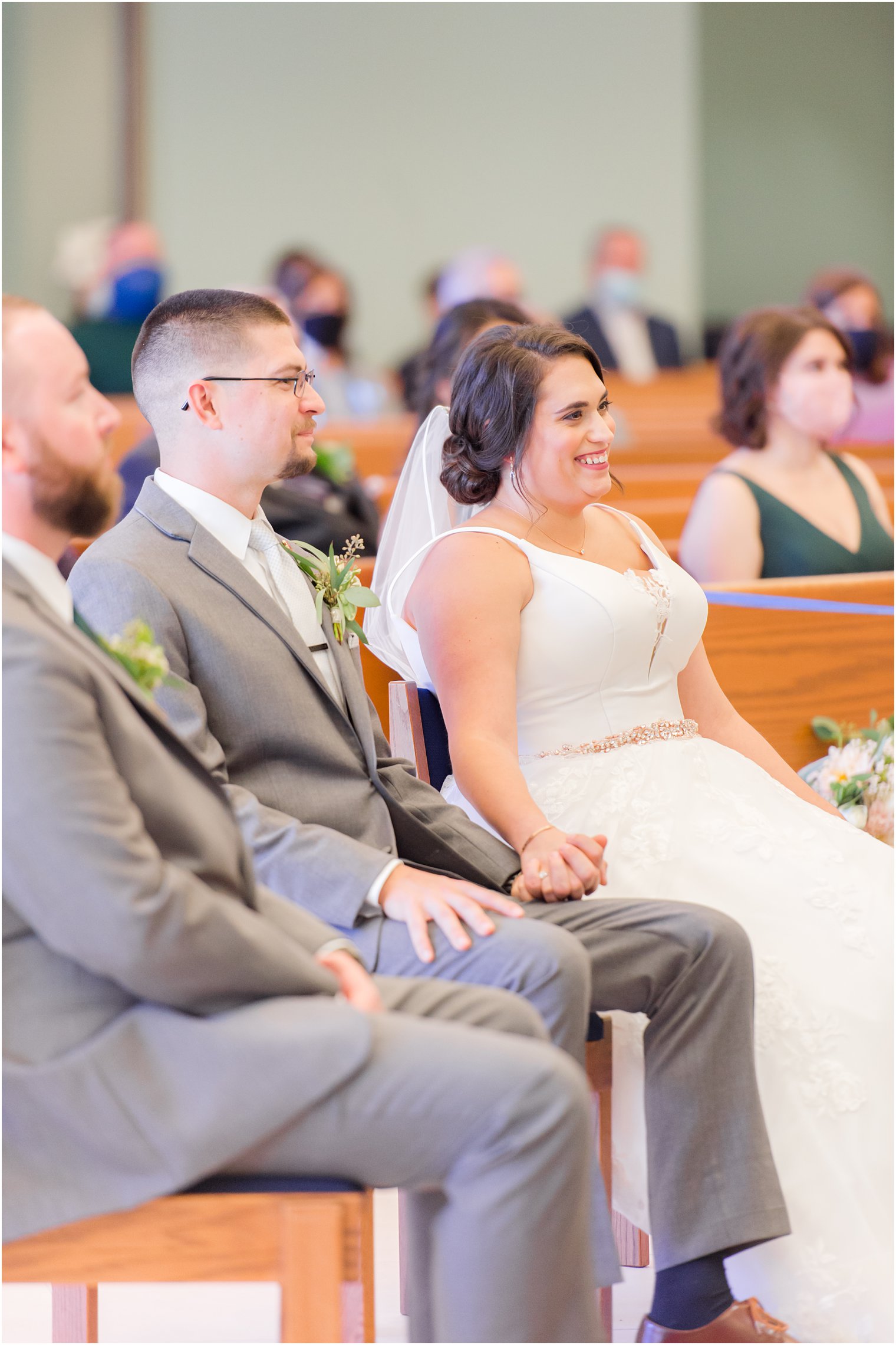 bride and groom sit in pew during traditional church wedding in New Jersey