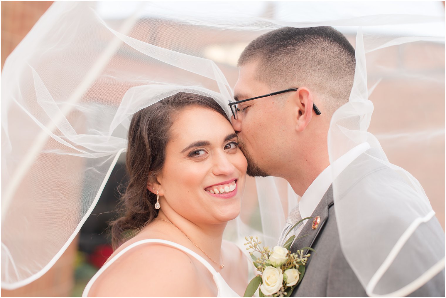 groom kisses bride's cheek under veil during NJ wedding photos