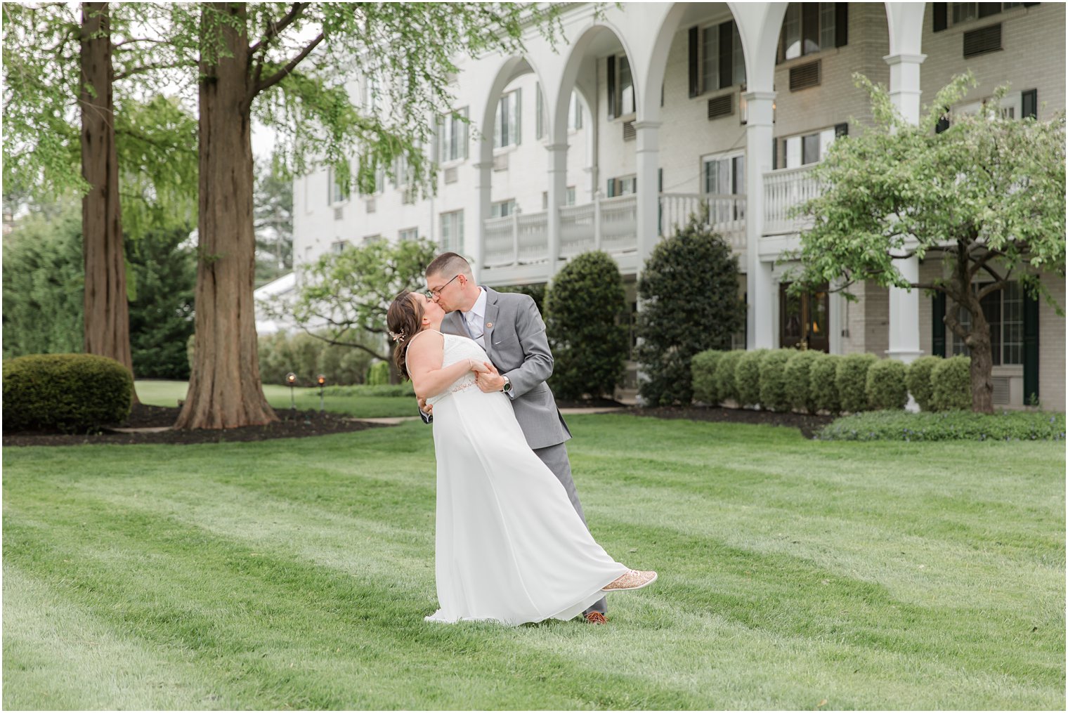 groom kisses bride on lawn of The Madison Hotel in Morristown NJ