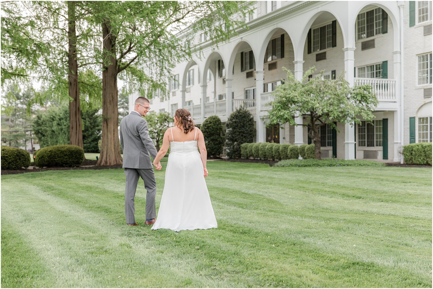 newlyweds walk along lawn outside The Madison Hotel