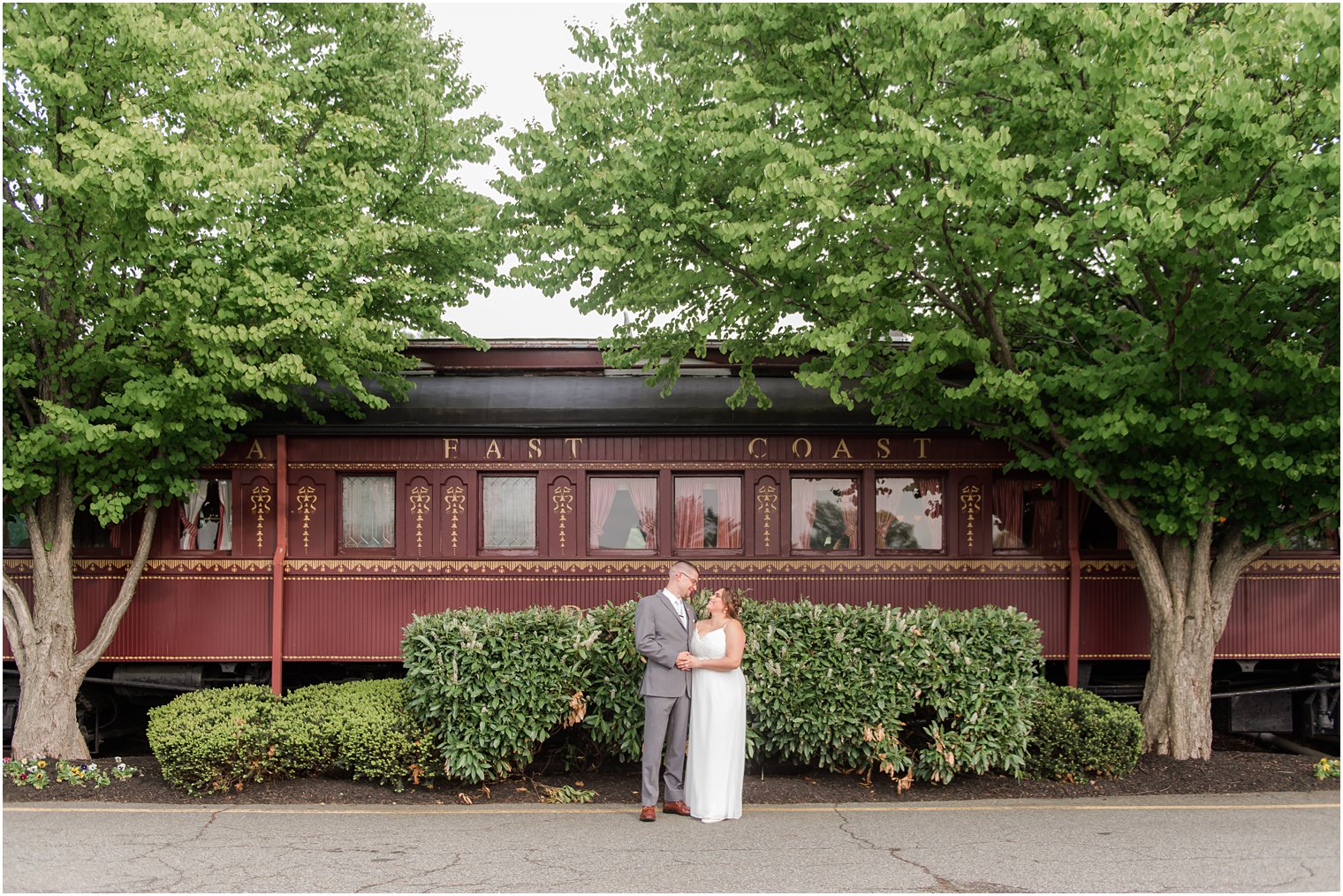 newlyweds pose by old train car at The Madison Hotel