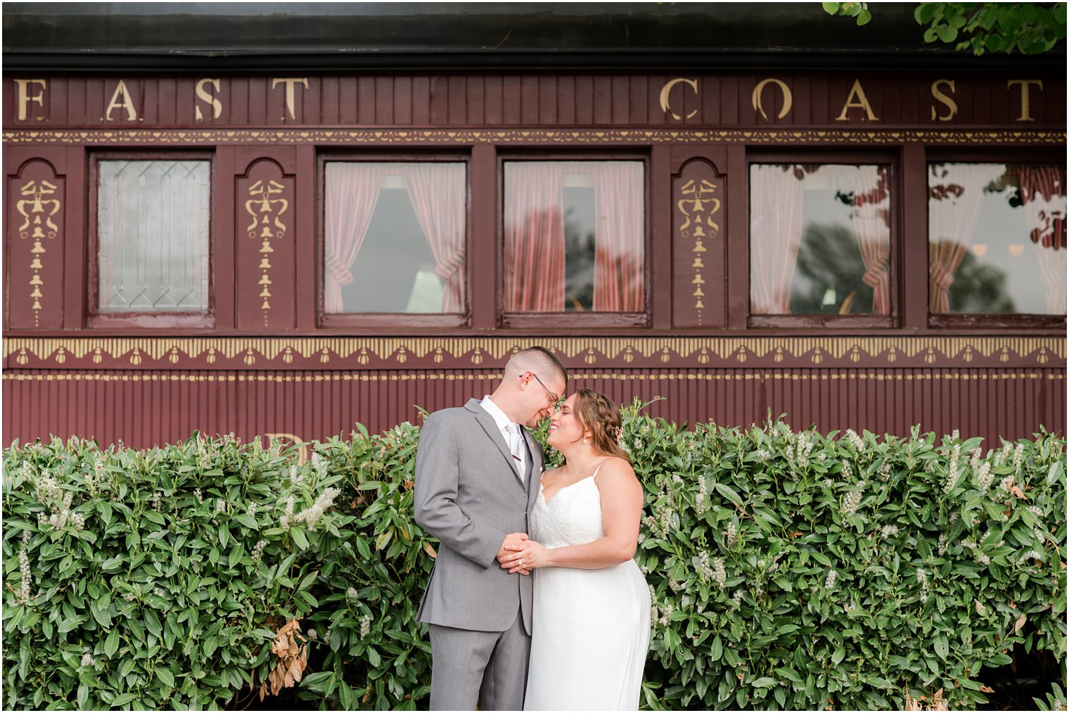 bride and groom pose outside old train car at The Madison Hotel