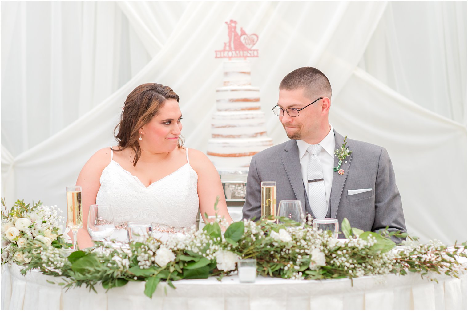 bride and groom smile at each other at sweetheart table in The Madison Hotel atrium