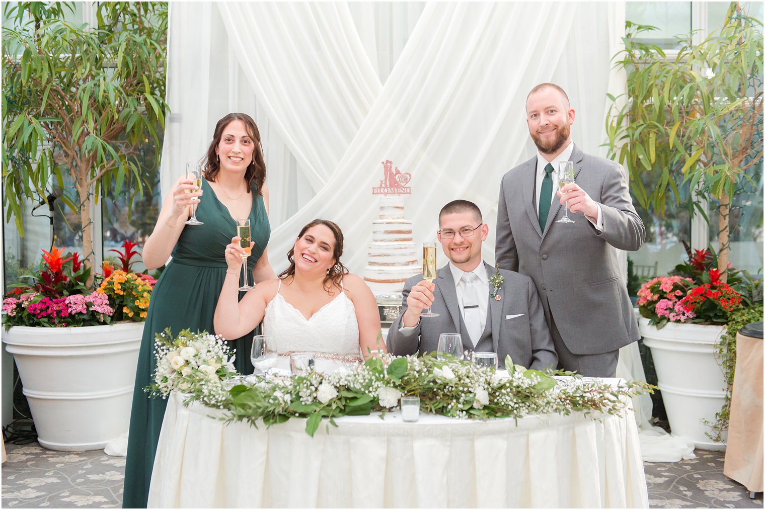 bride and groom pose with best man and maid of honor at sweetheart table