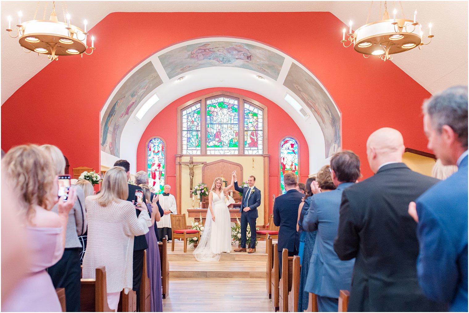 bride and groom cheer after wedding ceremony in red church