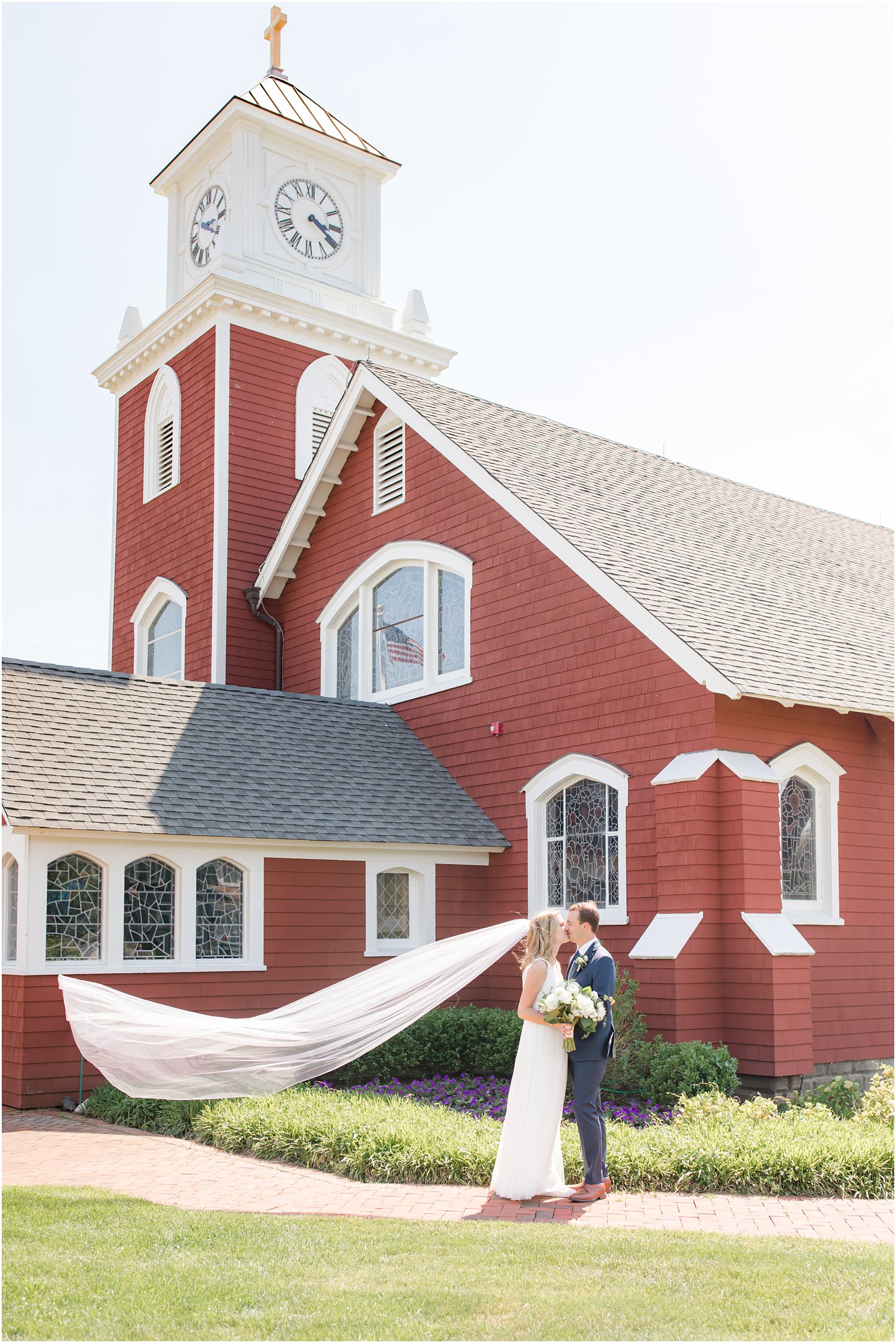 bride and groom kiss outside red church in New Jersey 