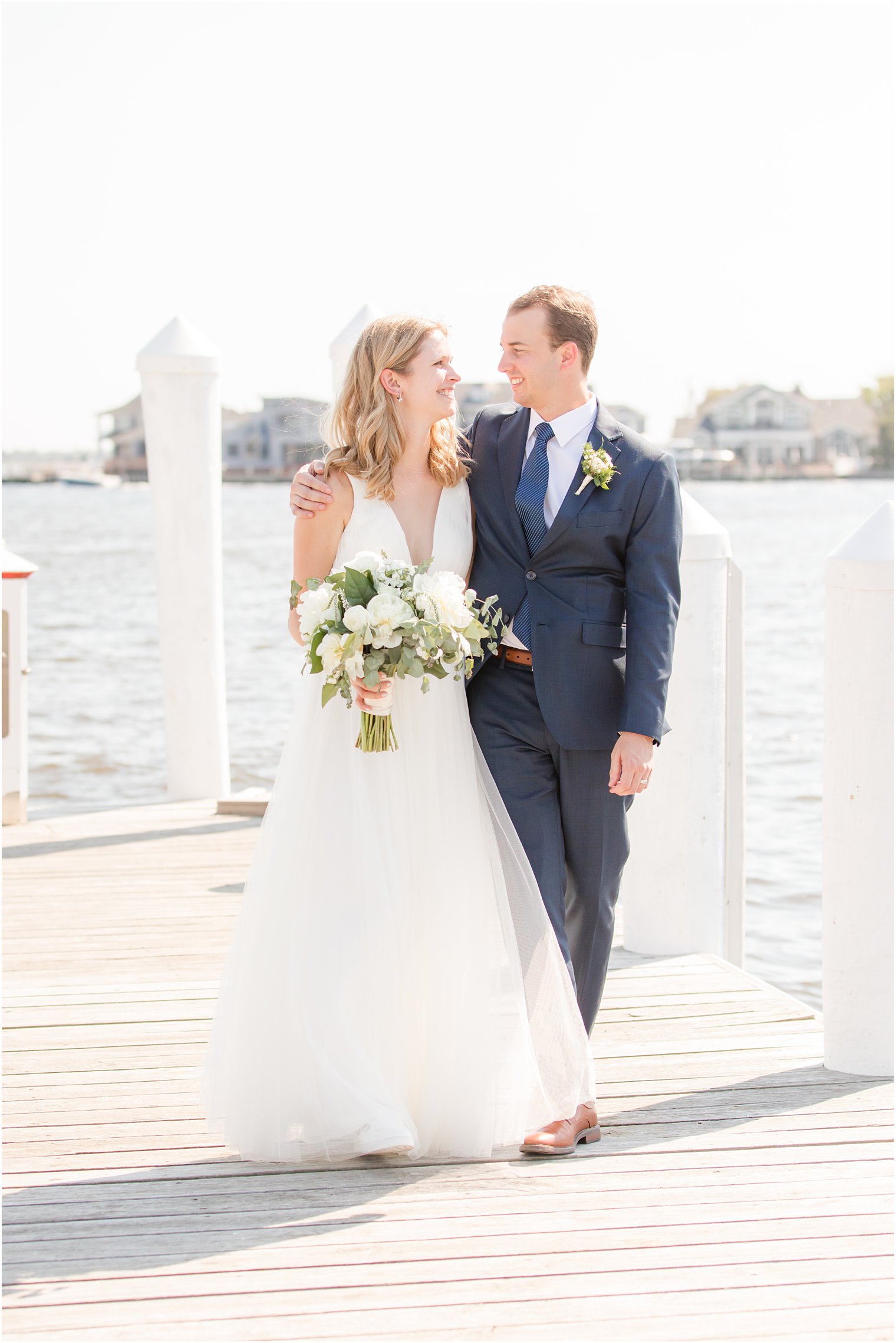 newlyweds hug each other walking down dock at Bay Head Yacht Club