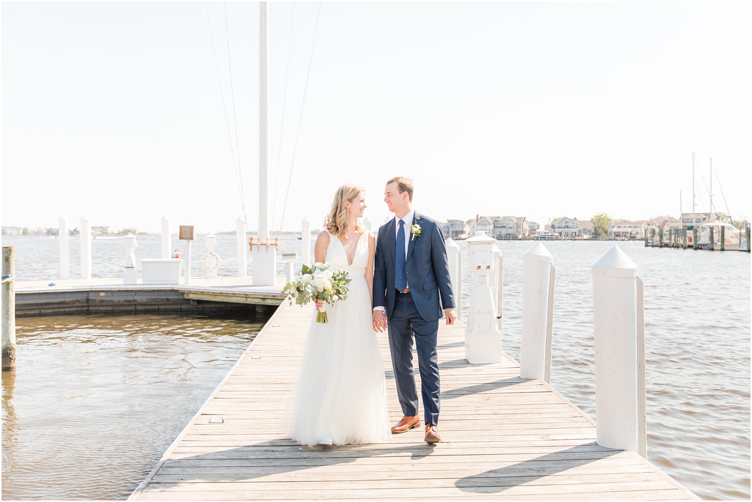 newlyweds hold hands walking on pier in Bay Head, NJ