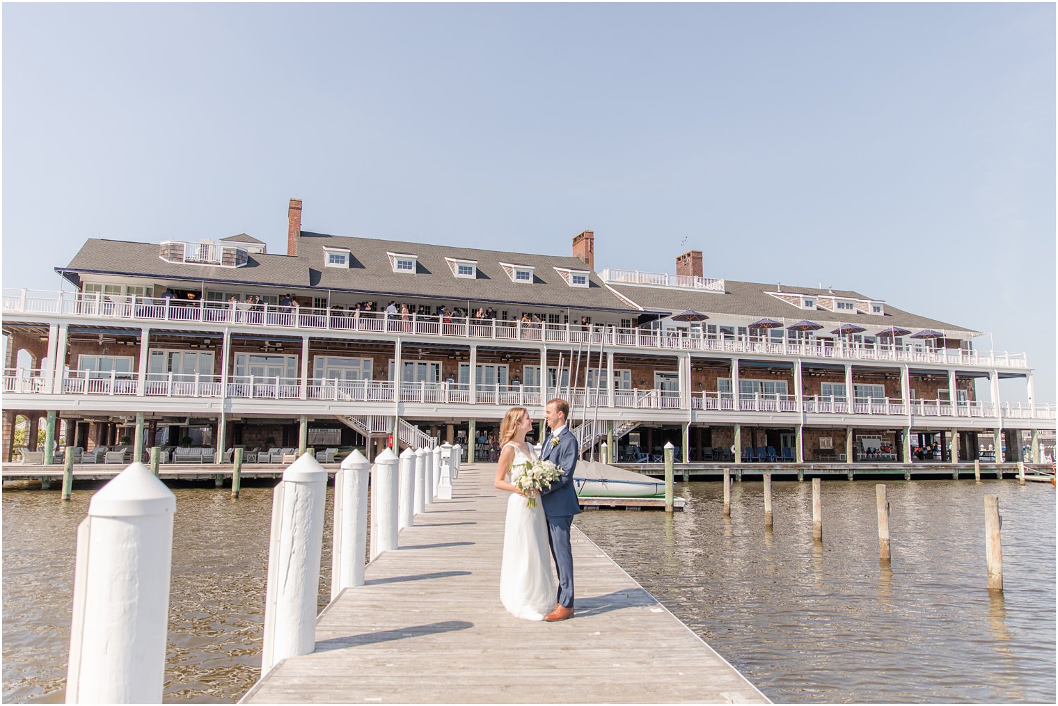 newlyweds pose outside Bay Head Yacht Club on pier 