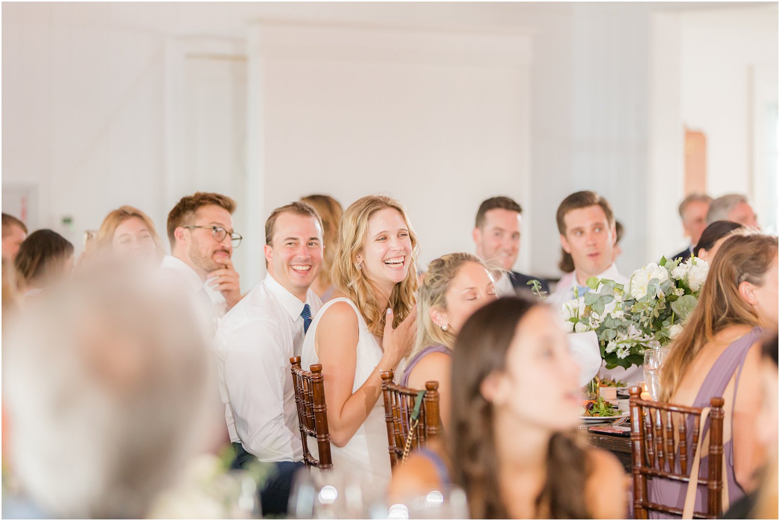 bride laughs with groom during wedding reception toasts 