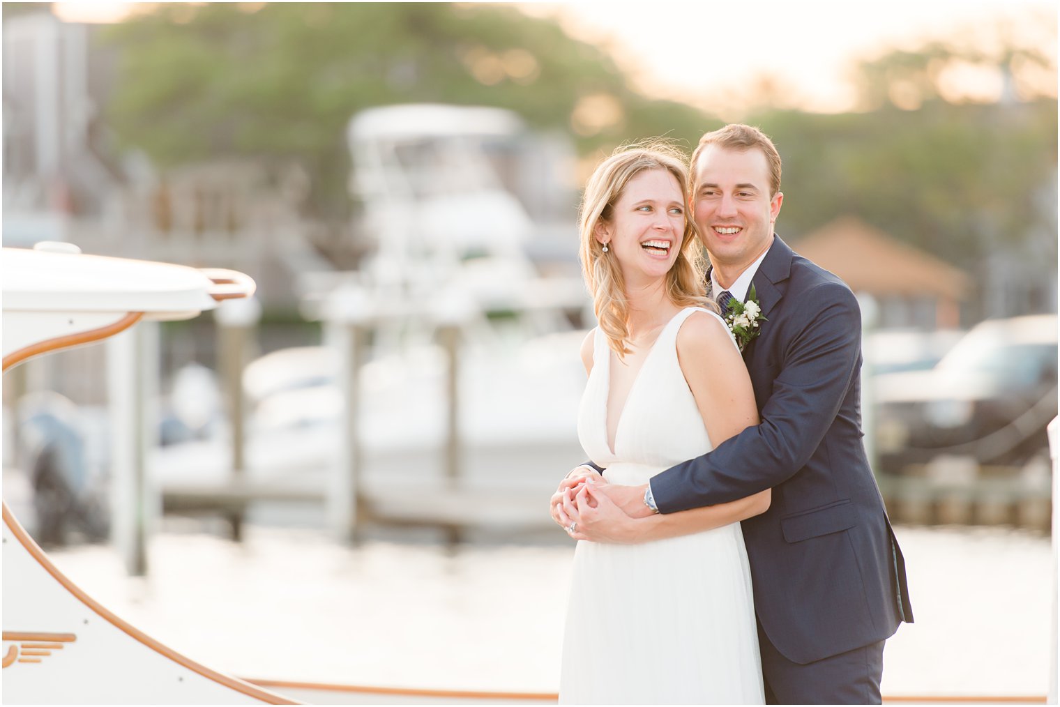 sunset wedding portraits of bride and groom hugging by boat in Bay Head, NJ