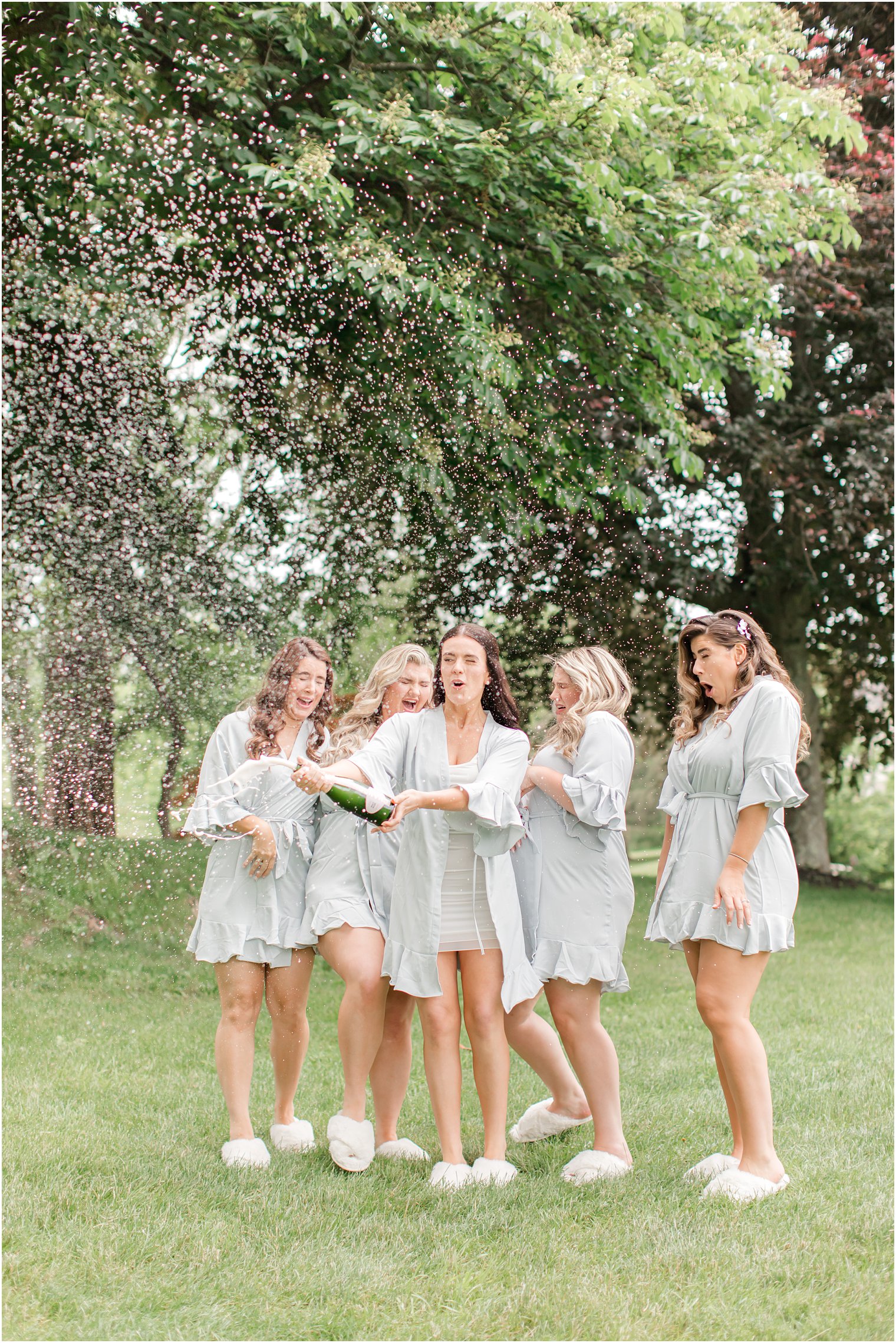 bride popping champagne with bridesmaids