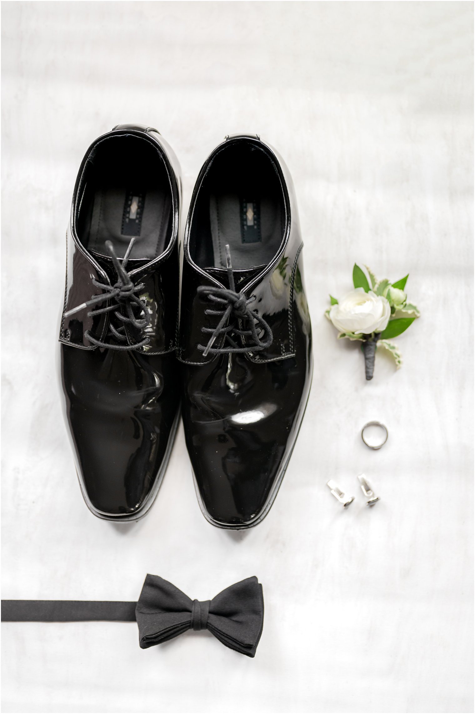elegant black tie wedding groom details on gray flatlay 