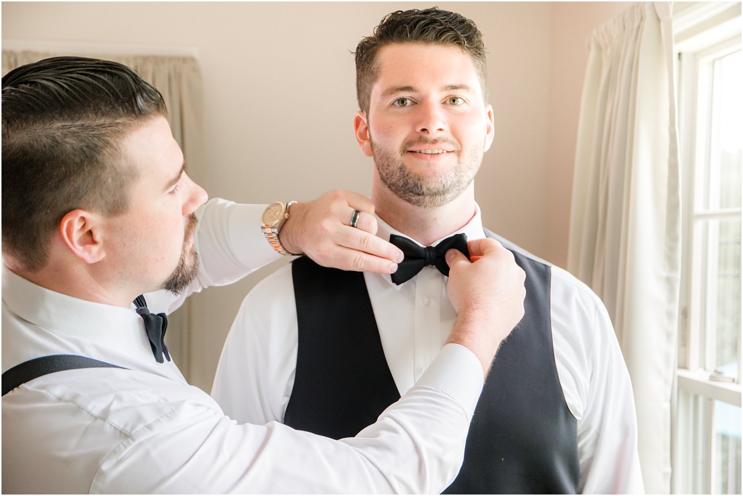 best man straightening out groom's bow tie