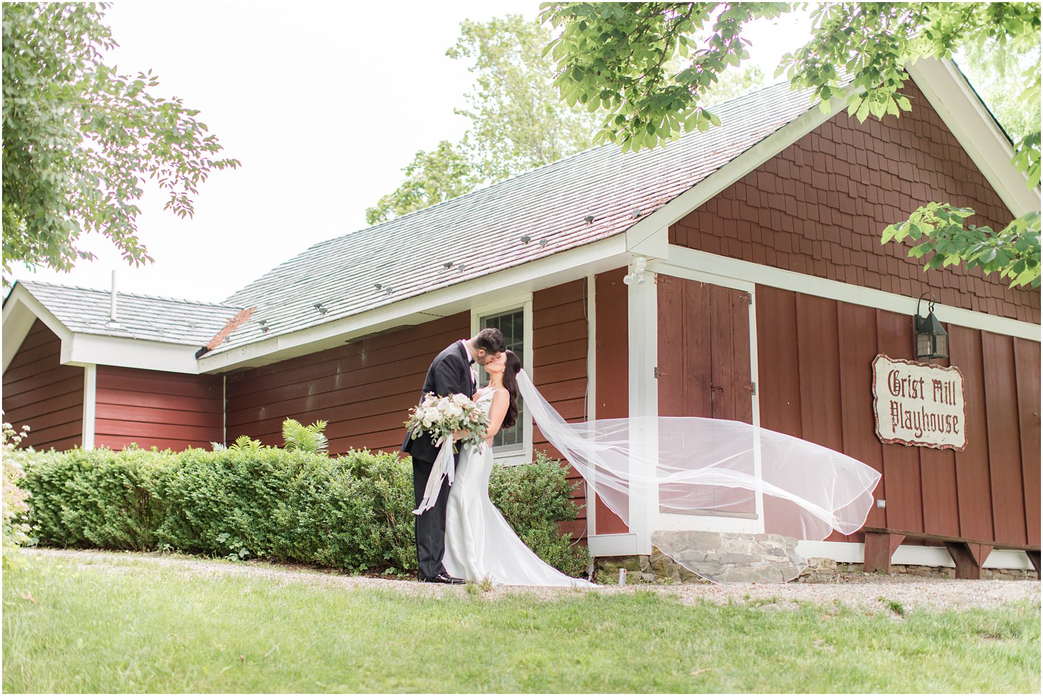 bride and groom kissing with veil blowing in the wind at Crossed Keys Estate