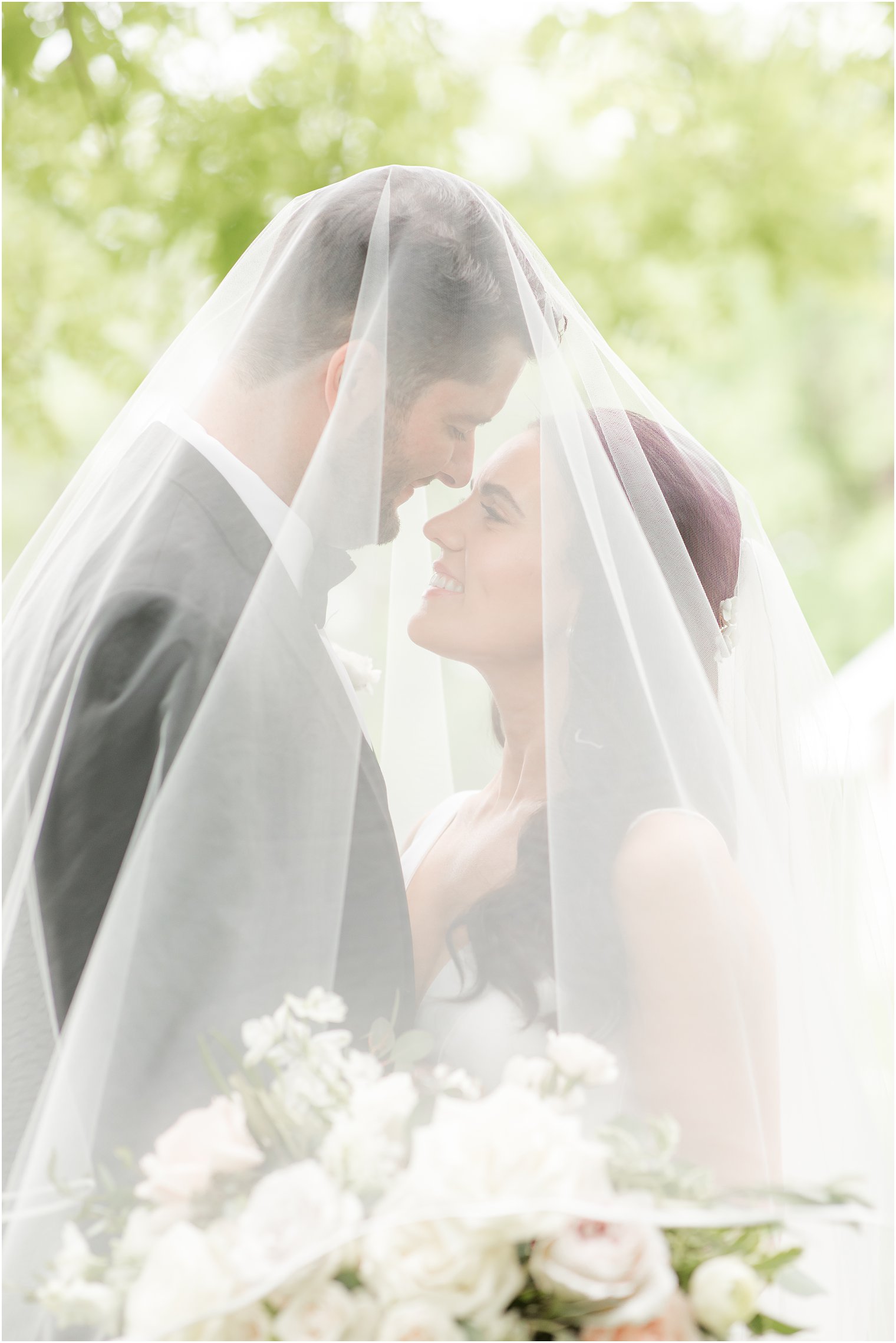 romantic portrait of bride and groom under a veil