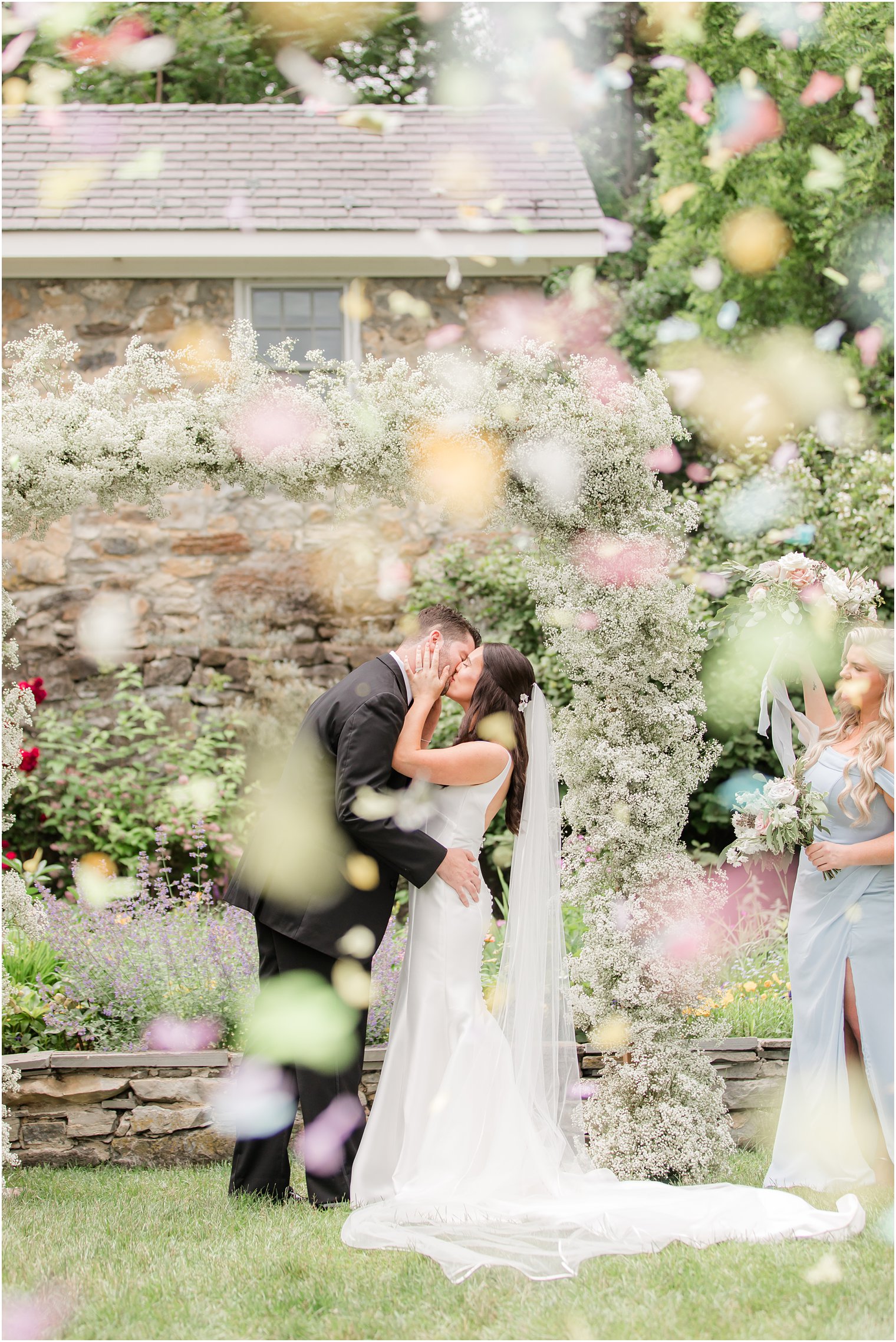 bride and groom kissing during ceremony with confetti flying through the air