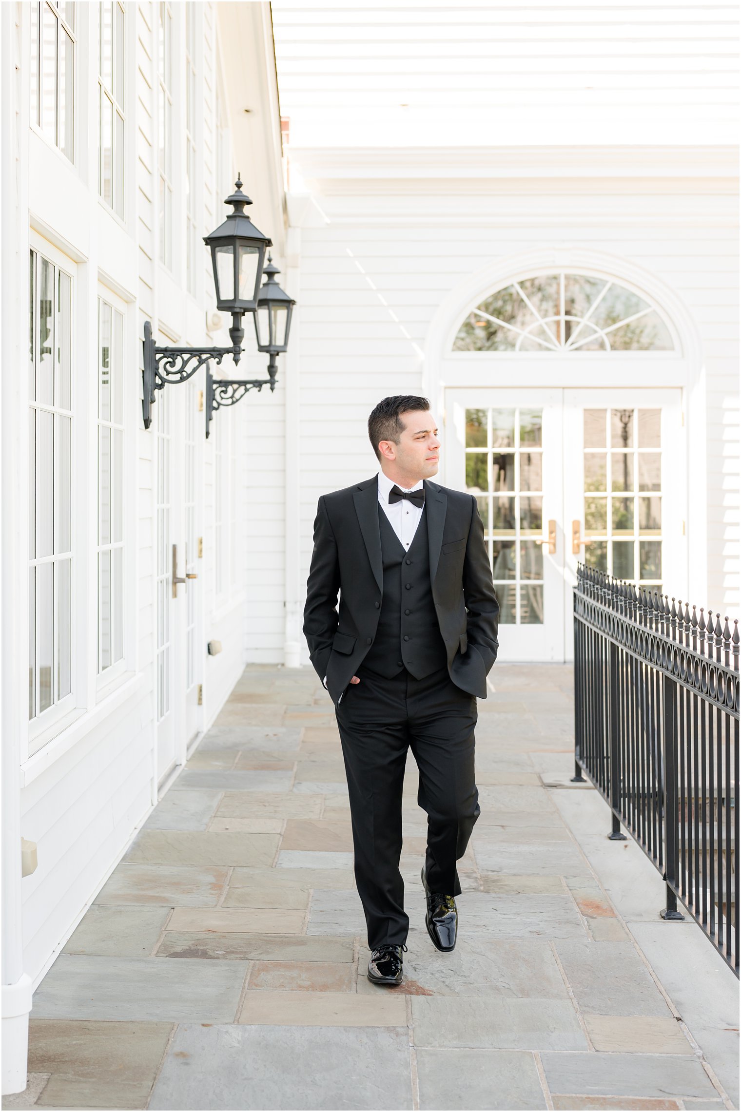 groom walks in classic black tux with bowtie at Park Savoy Estate