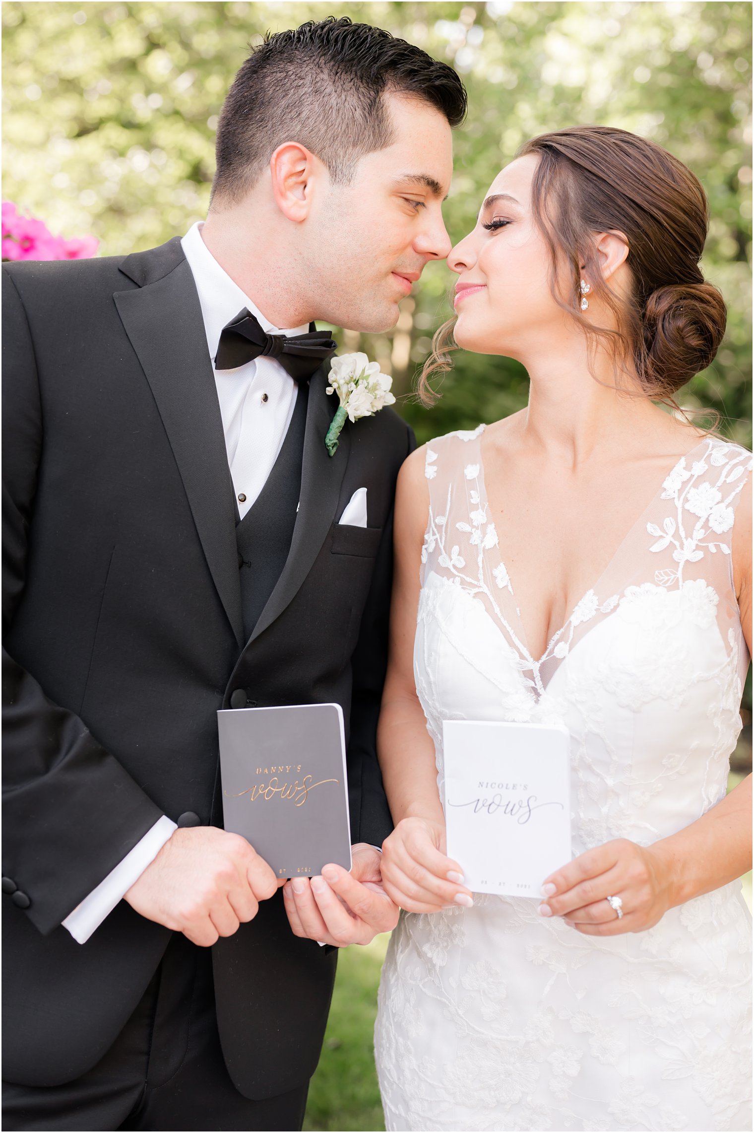 bride and groom hold vow booklets while looking at each other 