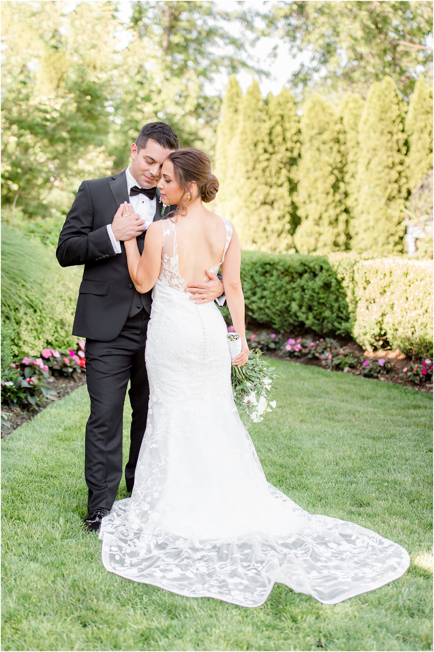 bride faces groom with hand on chest showing off back of gown 