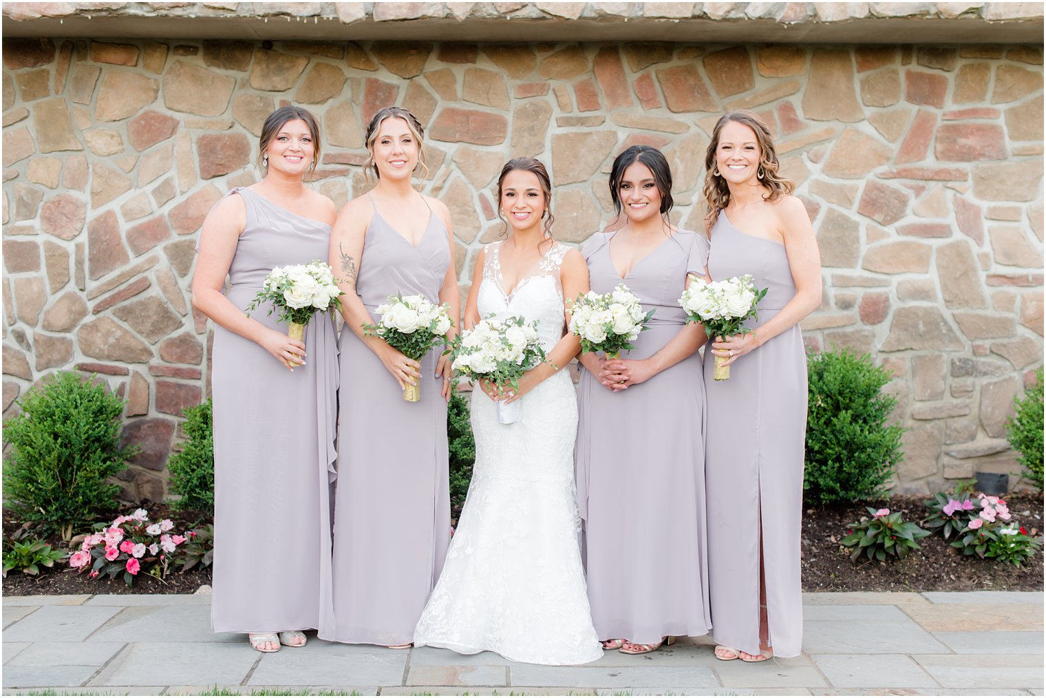 bride poses with four bridesmaids in grey dresses 