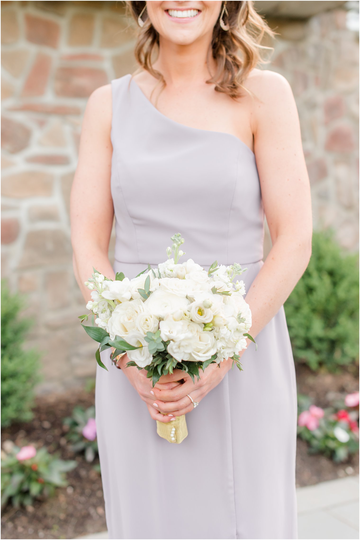 bridesmaid in grey dress holds bouquet of all white flowers