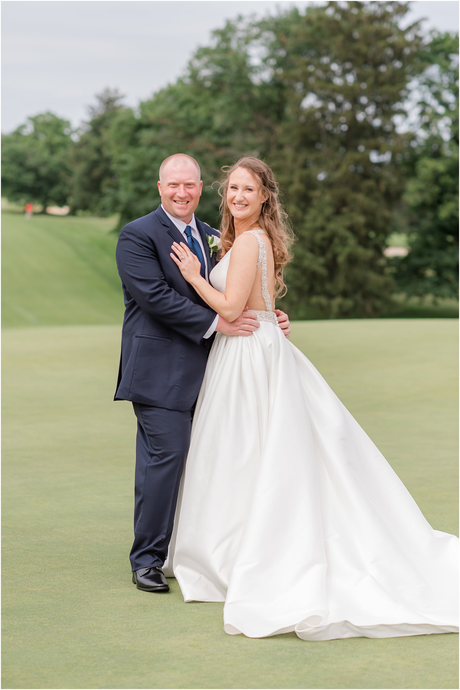 groom hugs bride to him while she rests her hands on his chest at Forsgate Country Club