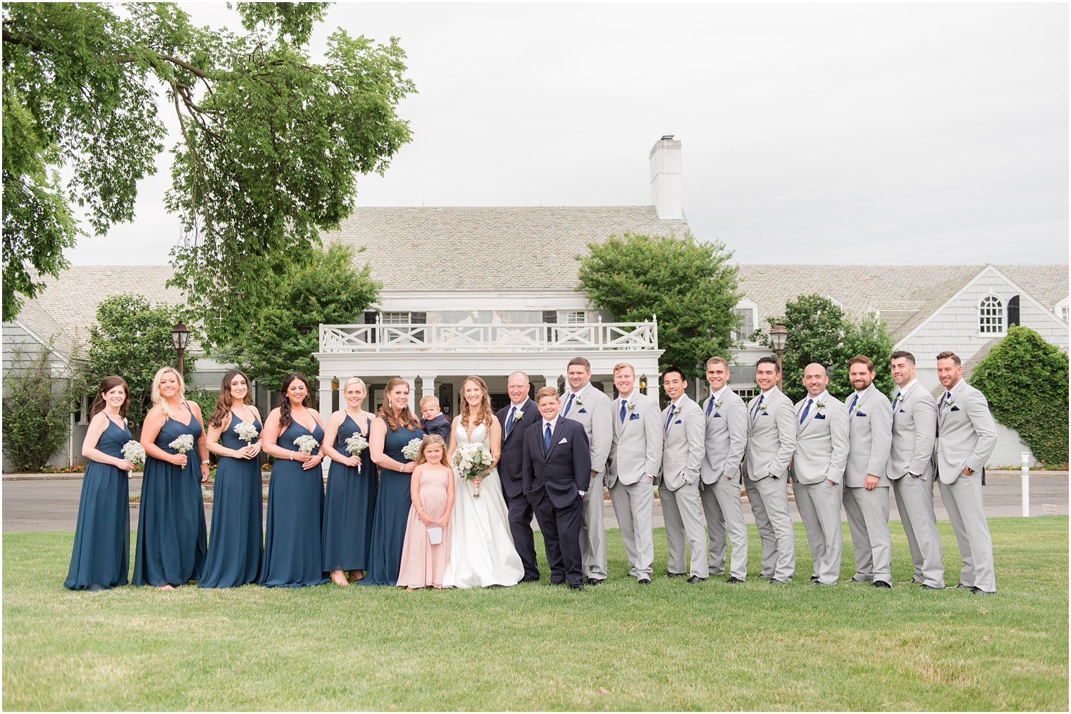 newlyweds pose with wedding party outside Forsgate Country Club