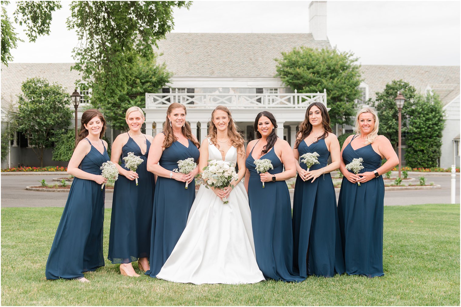 bride and bridesmaids in teal pose together outside Forsgate Country Club