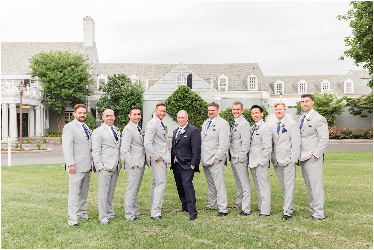 groom poses with groomsmen in grey suits