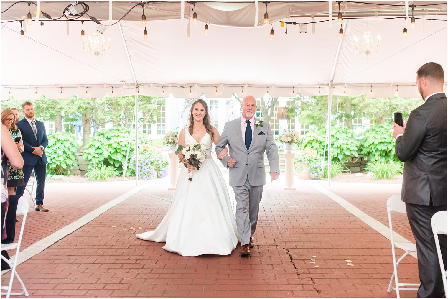 bride walks into tented wedding ceremony at Forsgate Country Club 