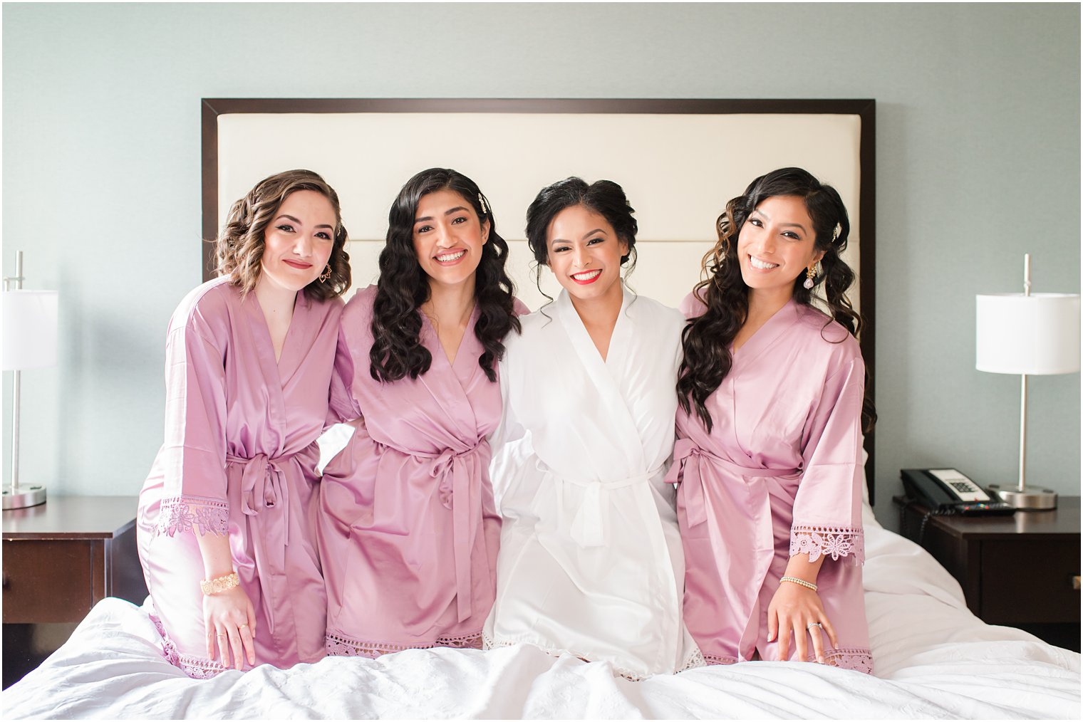 bride poses with three bridesmaids before NJ wedding