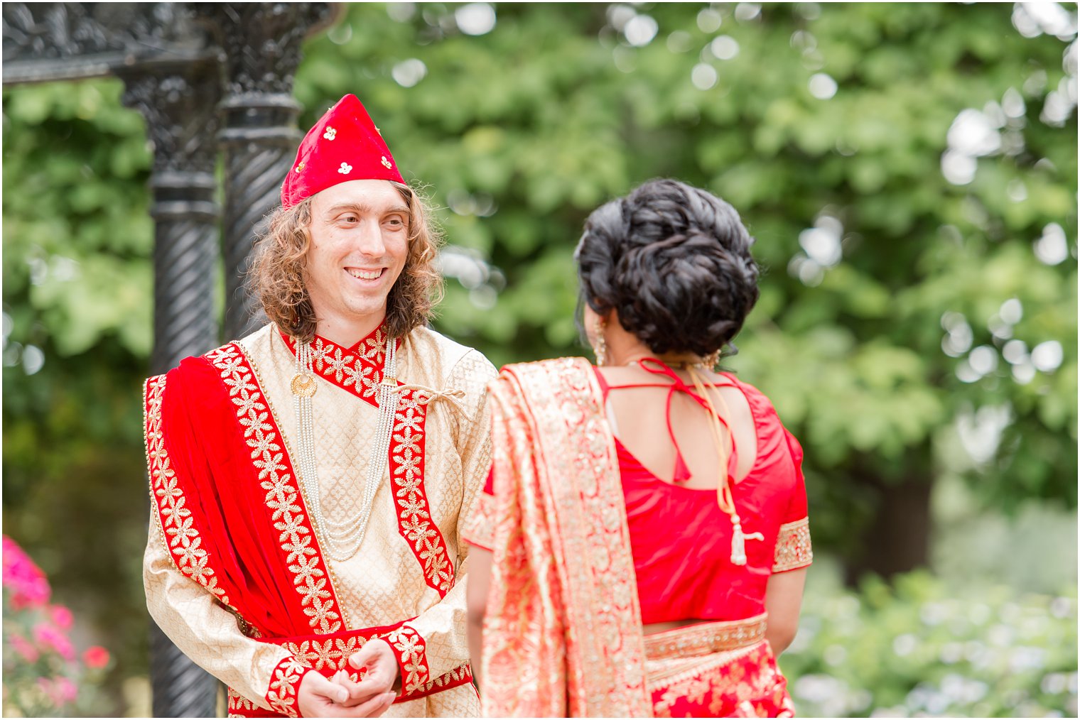 groom smiles at bride during first look in traditional Hindu wedding attire 