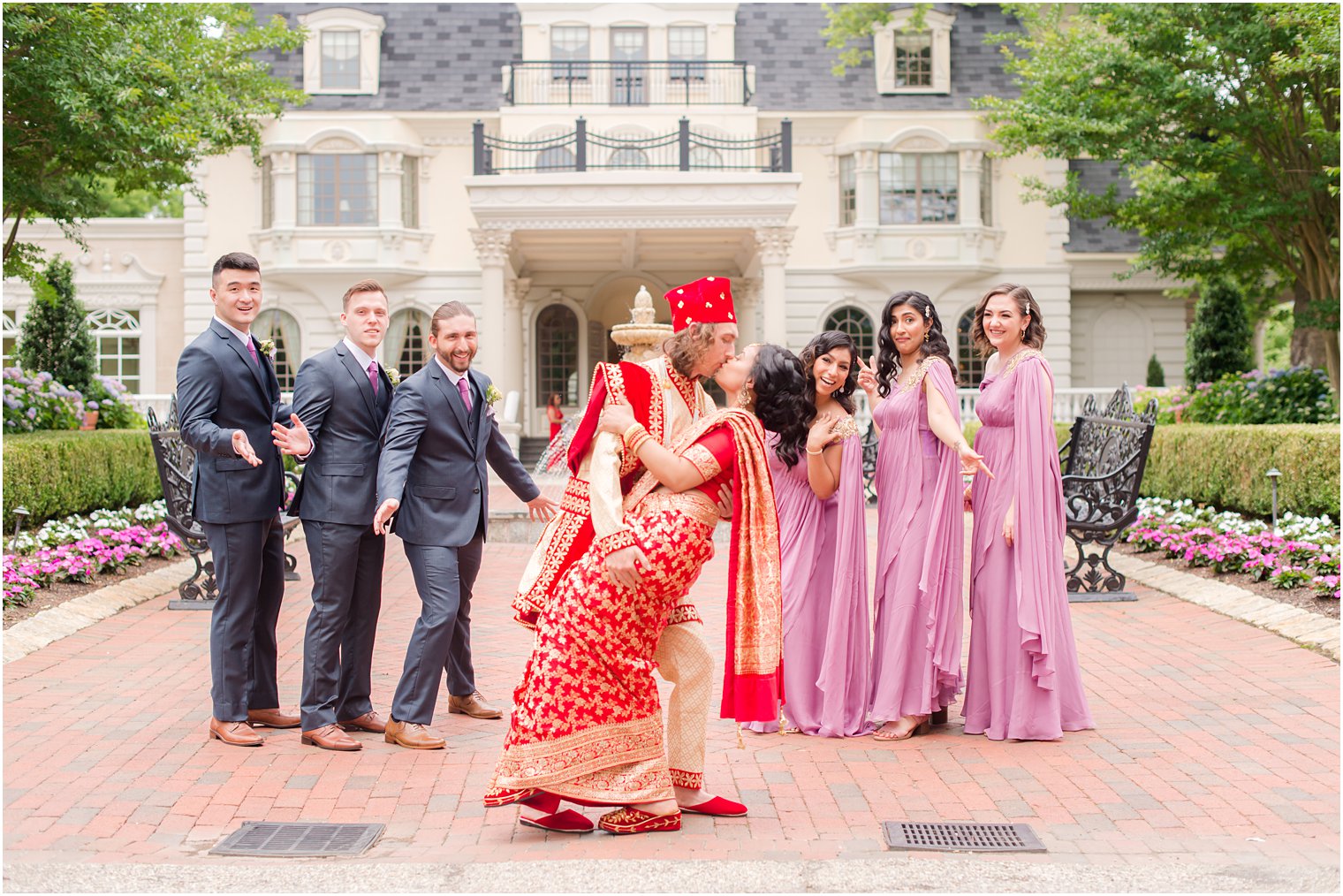 groom kisses bride dipping her during portraits with wedding party 