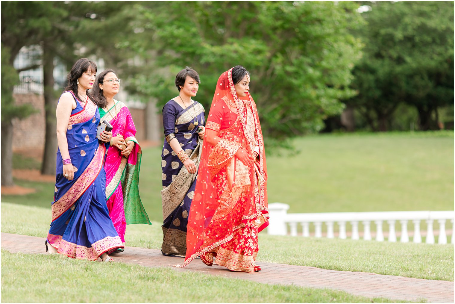 bride walks down aisle with family in traditional Hindu attire 