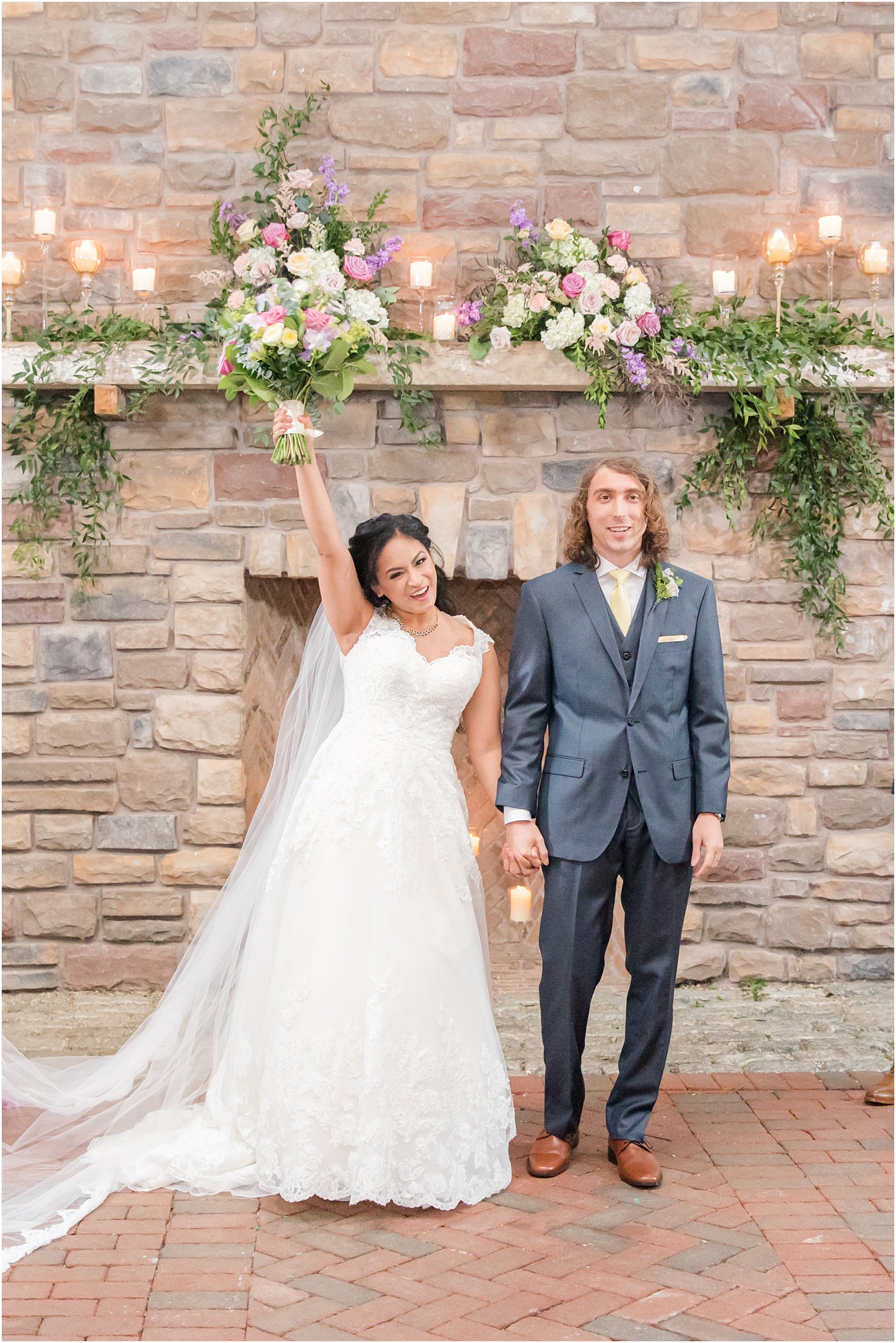 bride cheers during ceremony by stone fireplace 