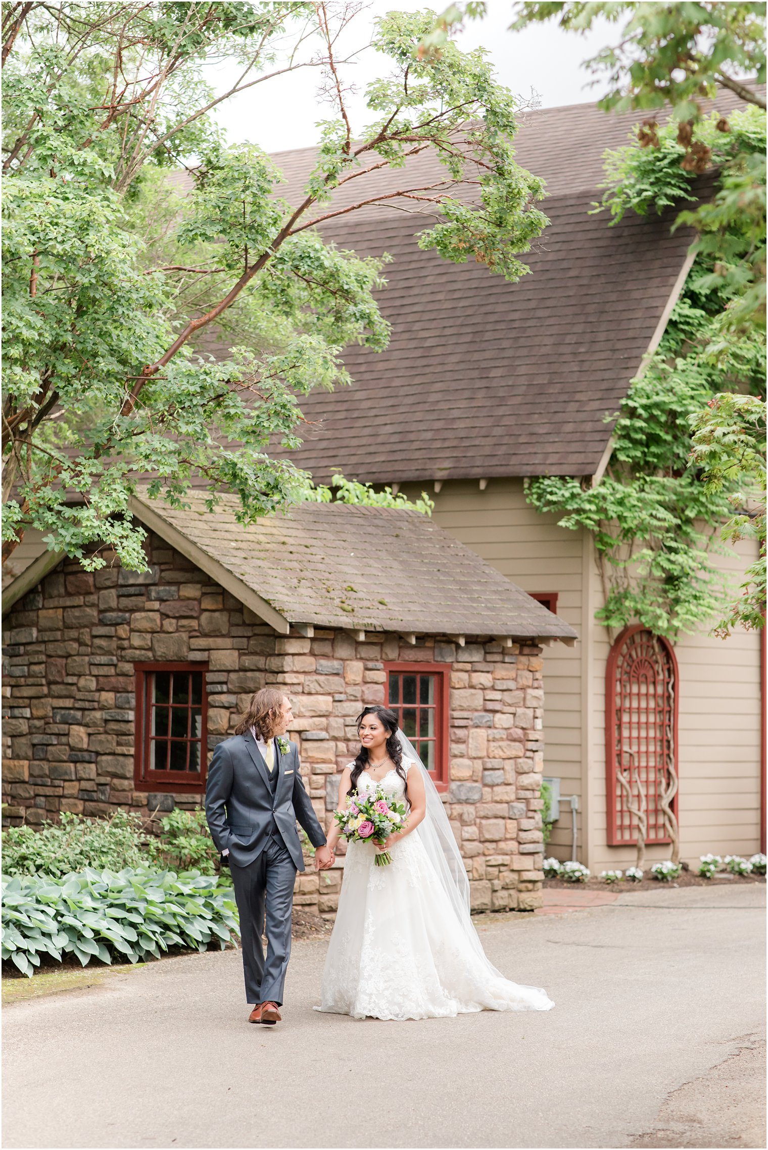 newlyweds walk along stone building at Ashford Estate