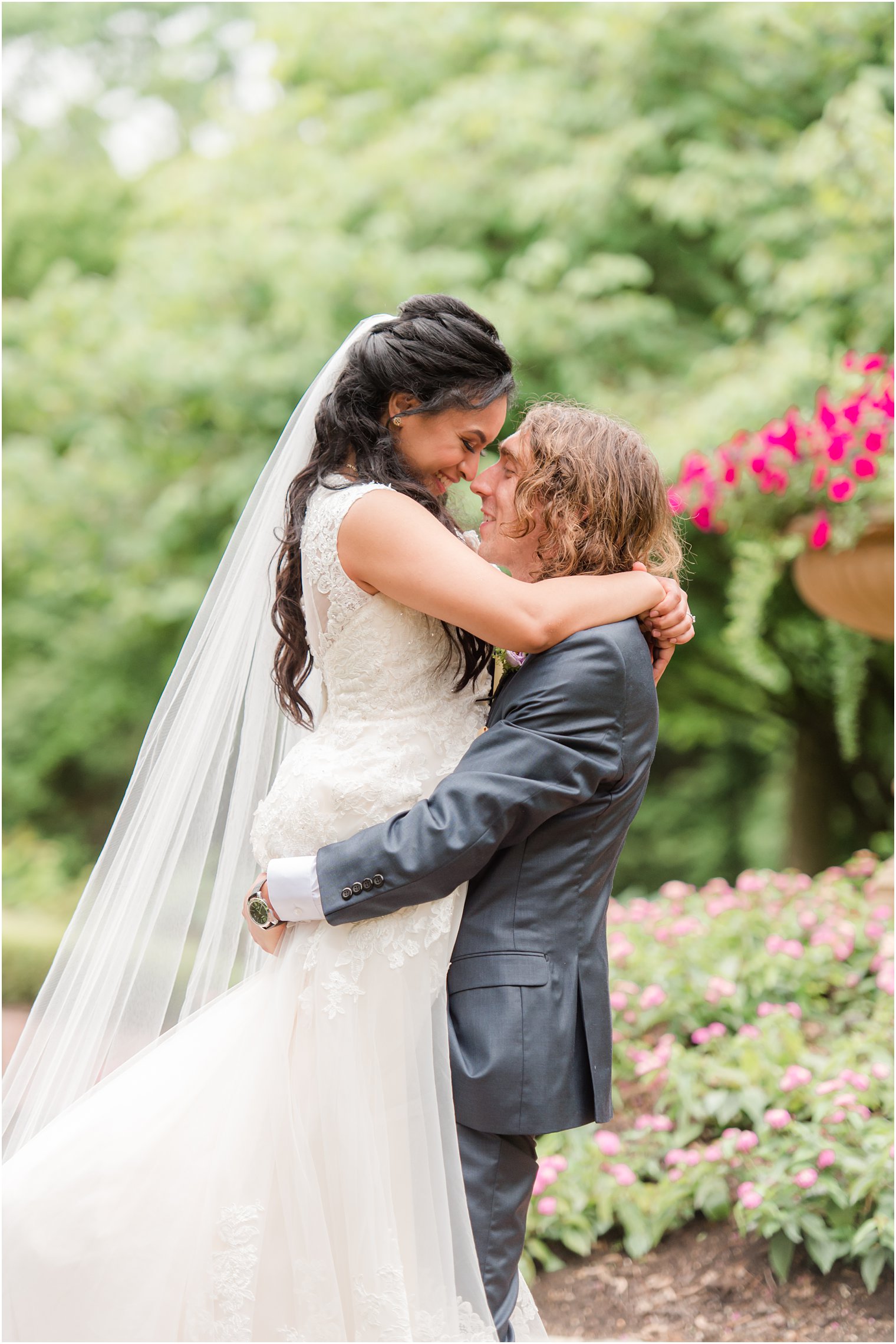 groom lifts up bride during wedding portraits in gardens of Ashford Estate